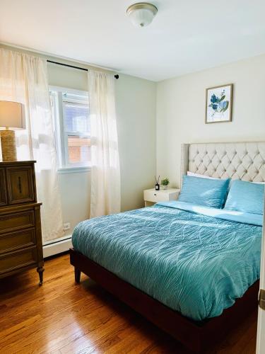a bedroom with a bed with blue sheets and a window at Charming and Convenient 3br 1ba apt - fully furnished and equipped - fast Internet in Forest Park