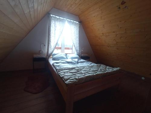 a bed in a wooden room with a window at Pele vendégház in Velem