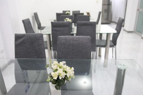 uma mesa de vidro com cadeiras e um vaso de flores sobre ela em Hotel Loyalty Moquegua em Moquegua