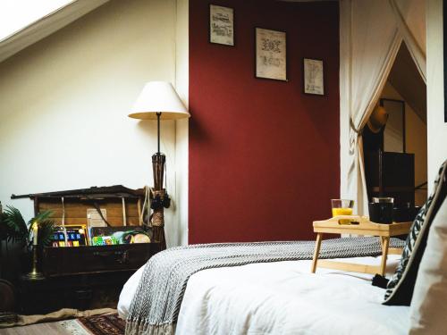 - une chambre avec des murs rouges, un lit et une table dans l'établissement L'aventurier, nuit insolite et hors du temps !, à Saumur
