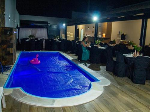 Eine Frau steht neben einem blauen Pool in einem Zimmer. in der Unterkunft Casa de lazer km eventos in Uberaba