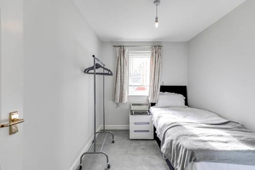 a white bedroom with a bed and a window at Welwyn Garden City Apartment by Mantis in Welwyn Garden City