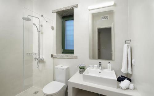 a white bathroom with a toilet and a sink at Triad Villas in Ioulis
