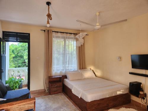 a bedroom with a bed and a tv and a window at Adhiambo's Studio near Bofa Beach in Kilifi