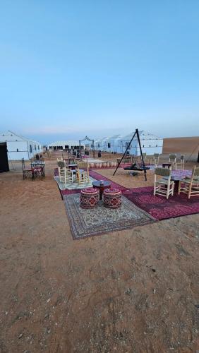 Najma Luxury Camp في مرزوقة: مجموعة من الطاولات والكراسي على الشاطئ