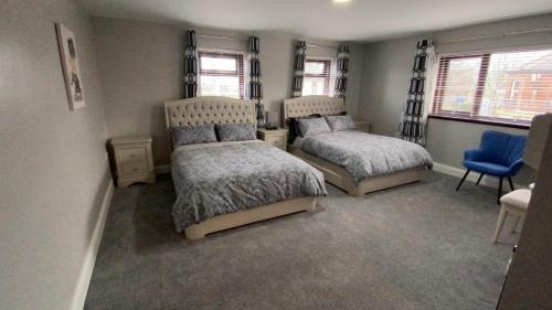 1 dormitorio con 2 camas y silla azul en Johnny Murphy's Guest Rooms en Meigh
