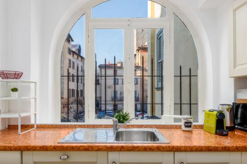 uma cozinha com um lavatório e uma grande janela em [near Funicolar] Bergamo Alta Design HOUSE 1 em Bérgamo