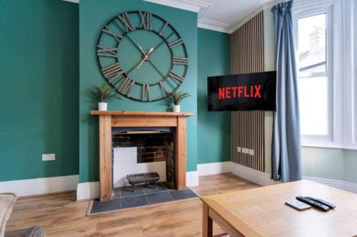 a living room with a large clock on the wall at Spacious House - Sleeps 10 - Central Location - Free Parking, Fast WiFi and Smart TV with Nerflix by Yoko Property in Northampton