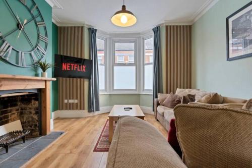 a living room with a couch and a clock on the wall at Spacious House - Sleeps 10 - Central Location - Free Parking, Fast WiFi and Smart TV with Nerflix by Yoko Property in Northampton