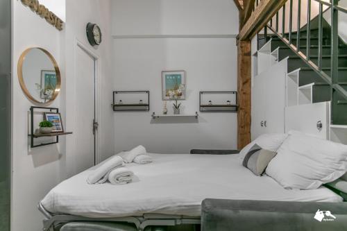 Cette chambre blanche dispose d'un lit et d'un escalier. dans l'établissement MBA - Splendide Appart - Patay 3 - Proche Bercy, à Paris