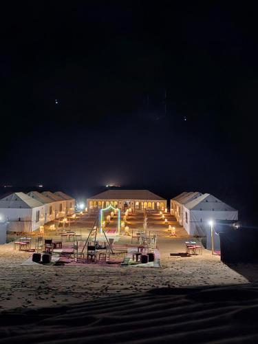 a group of buildings with a playground at night at Najma Luxury Camp in Merzouga