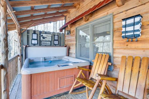 a cabin with a hot tub and two chairs at Quaint Dahlonega Cabin with Cavenders Creek Access! in Dahlonega