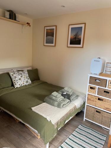 a bedroom with a green bed and a shelf at The Cotswold Nook in Dursley