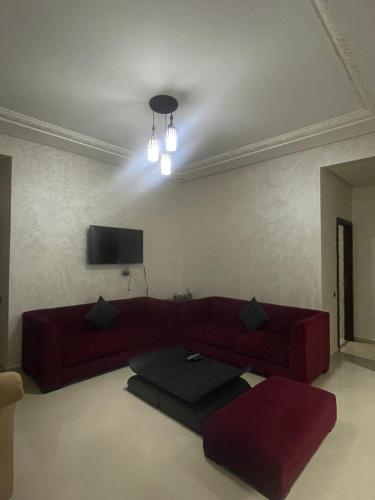 uma sala de estar com um sofá vermelho e uma televisão em appartement moderne em Minaret de Mansuria