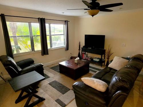 sala de estar con muebles de cuero y TV de pantalla plana en Cozynest2 en Boynton Beach