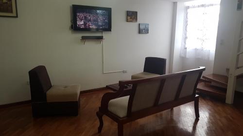 een woonkamer met een stoel en een televisie bij Departamento Dúplex Colonial in Quito