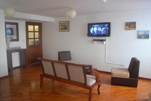 een kamer met een stoel en een tv aan de muur bij Departamento Dúplex Colonial in Quito