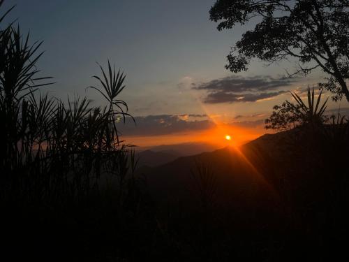 a sunset with the sun setting on a mountain at Reserva La Esperanza in Vergara