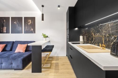 un soggiorno con divano blu e una cucina di Apartament Park Partynice a Breslavia