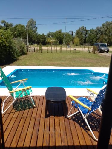 a deck with chairs and a table next to a pool at El Destino in San Miguel del Monte