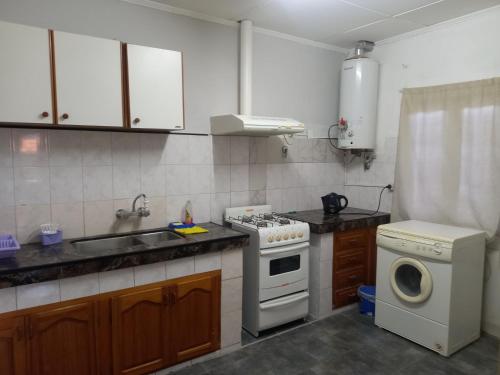 a kitchen with a stove and a sink and a washing machine at Departamento céntrico San Rafael in San Rafael