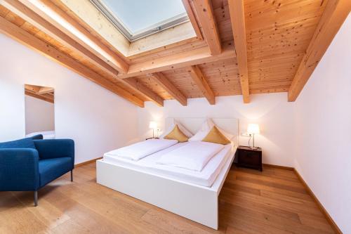 ein Schlafzimmer mit einem weißen Bett und einem blauen Stuhl in der Unterkunft Villa Marga Ferienwohnung Steinernes Meer in Schönau am Königssee