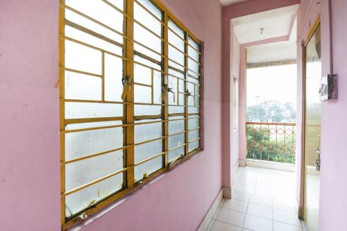 OYO Hotel Suvidha في جمشيدبور: غرفة بجدران وردية ونافذة كبيرة
