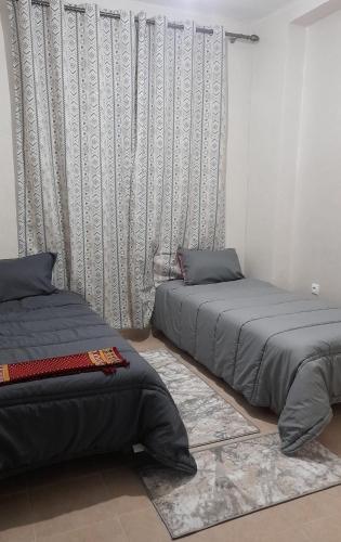 a bedroom with two beds and a curtain at RELAX IBN BATOUTA in Tangier
