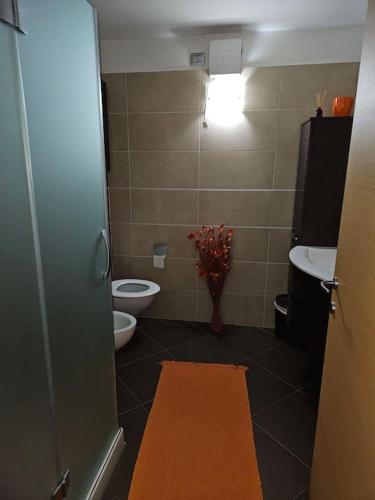 La salle de bains est pourvue de toilettes et d'un vase de fleurs. dans l'établissement casa vacanze Bondone, à Trente
