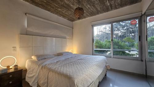 a bedroom with a bed and a large window at Apart Hotel El Caracol in José Ignacio