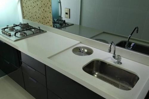 a kitchen counter with a sink and a stove at Apartamento Duplex (Cobertura) Praia do Forte in Cabo Frio