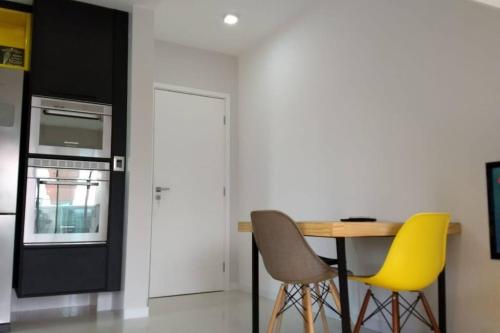 a kitchen with a table and two yellow chairs at Apartamento Duplex (Cobertura) Praia do Forte in Cabo Frio