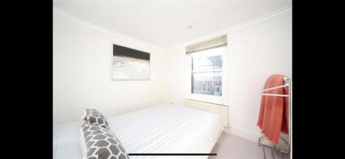 a white bedroom with a bed and a window at Cheery close in London