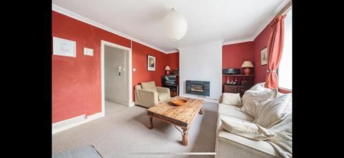 a living room with red walls and a couch and a table at Cheery close in London