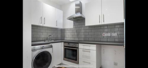 a white kitchen with a washing machine in it at Cheery close in London