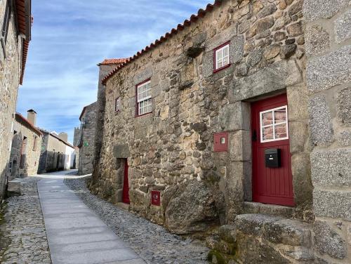 a stone building with a red door on a street at Recanto da Pedra in Linhares
