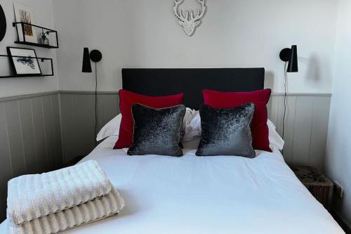 uma cama com almofadas vermelhas e pretas em The Old School House Retreat em Tibberton
