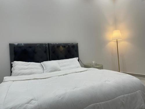una camera con letto bianco e testiera nera di شقة بغرفة وصالة a Hafr Al Baten