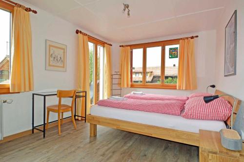 a bedroom with a bed and a desk and windows at Chalet Azeno OG in Adelboden
