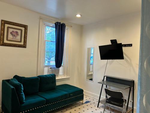 Private room في فيلادلفيا: غرفة معيشة بها أريكة خضراء وتلفزيون