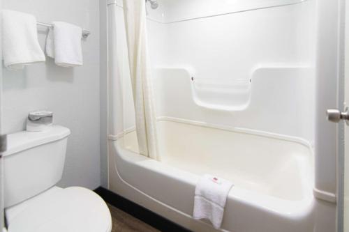 a white bathroom with a toilet and a bath tub at Motel 6-Lantana, FL in Lantana