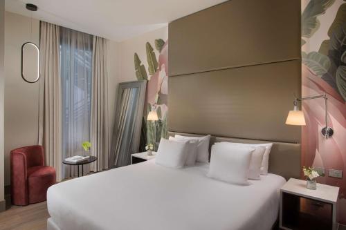 a bedroom with a large white bed and a red chair at NH Collection Milano Touring in Milan