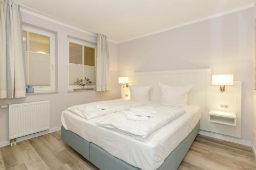 um quarto com uma grande cama branca e 2 candeeiros em Meeresblick Meeresblick 324 em Kühlungsborn