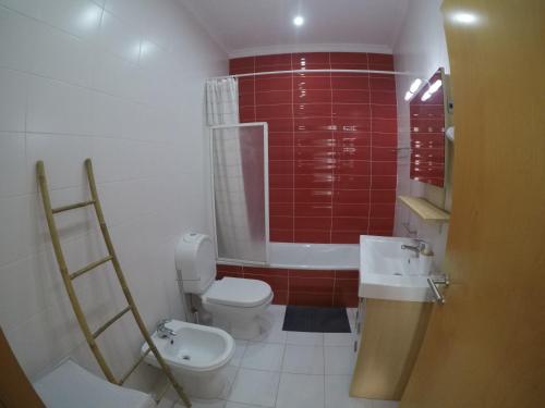 La salle de bains est pourvue de toilettes, d'un lavabo et de carrelage rouge. dans l'établissement Studios by Blue Door, à Portimão