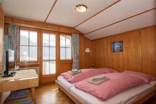1 dormitorio con 1 cama, escritorio y ventanas en Chalet Grimm en Adelboden