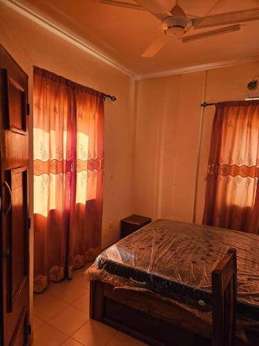 Schlafzimmer mit einem Bett mit orangefarbenen Vorhängen in der Unterkunft Hébergement VIP in Ouagadougou