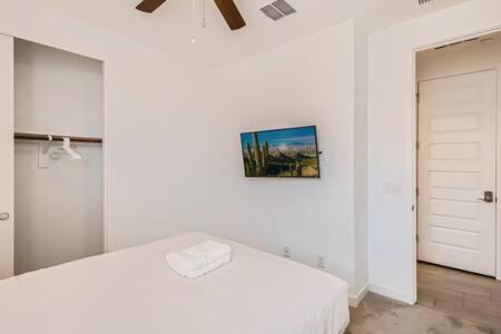 a white bedroom with a bed and a picture on the wall at NEW - 5BR Home 20 min from Phoenix - AT in Avondale