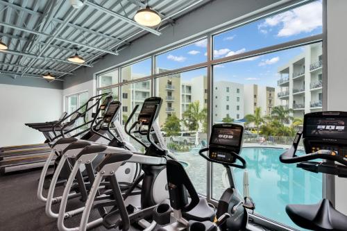 a gym with a row of treadmills and a swimming pool at Waterside Retreat: Modern 2BR, Mins to Beach & Apt in Sarasota