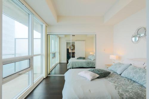 a bedroom with two beds and a large window at Skyline Elegance Condo in Toronto