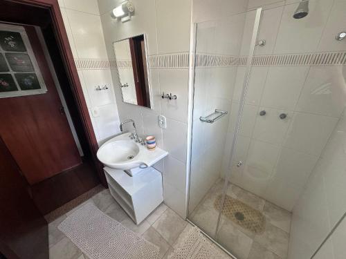 a white bathroom with a sink and a shower at Apartamento no centrinho para a família in Campos do Jordão